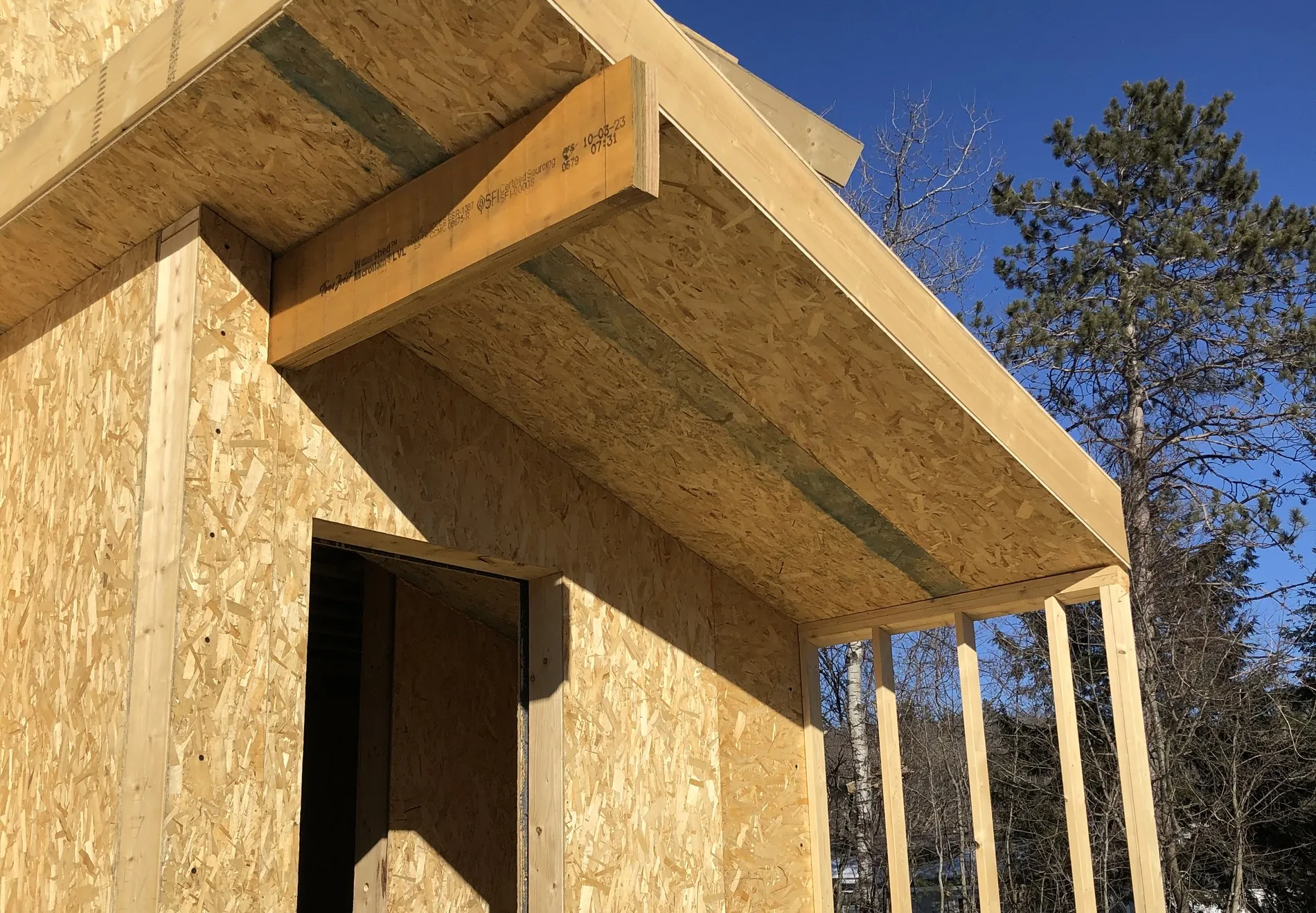 SIP eave in section on a PHIUS certified house — panel edge, sealed joint and LVL header against winter sky
